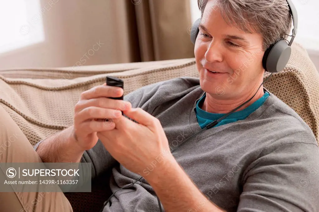 Mature man wearing headphones using cell phone