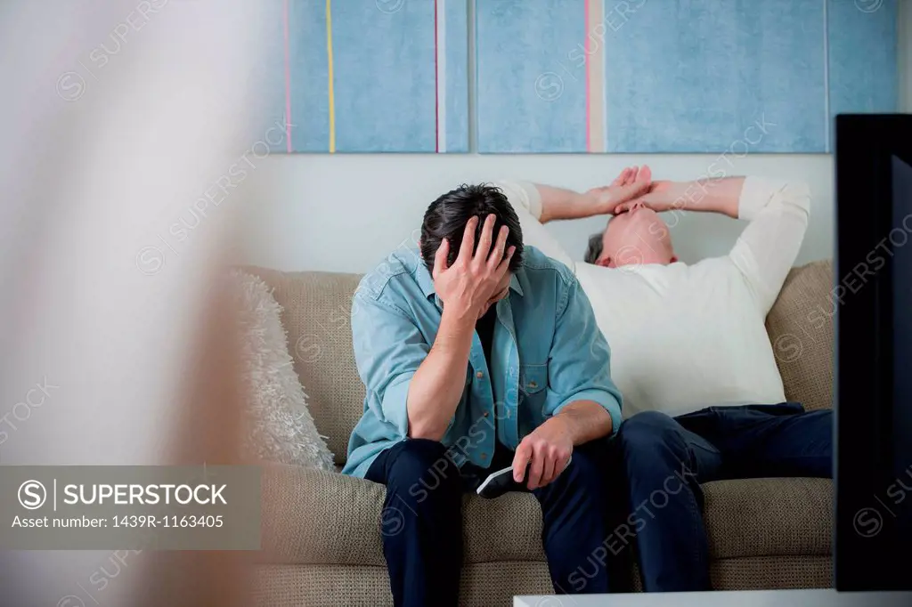 Mature men watching tv, head in hands