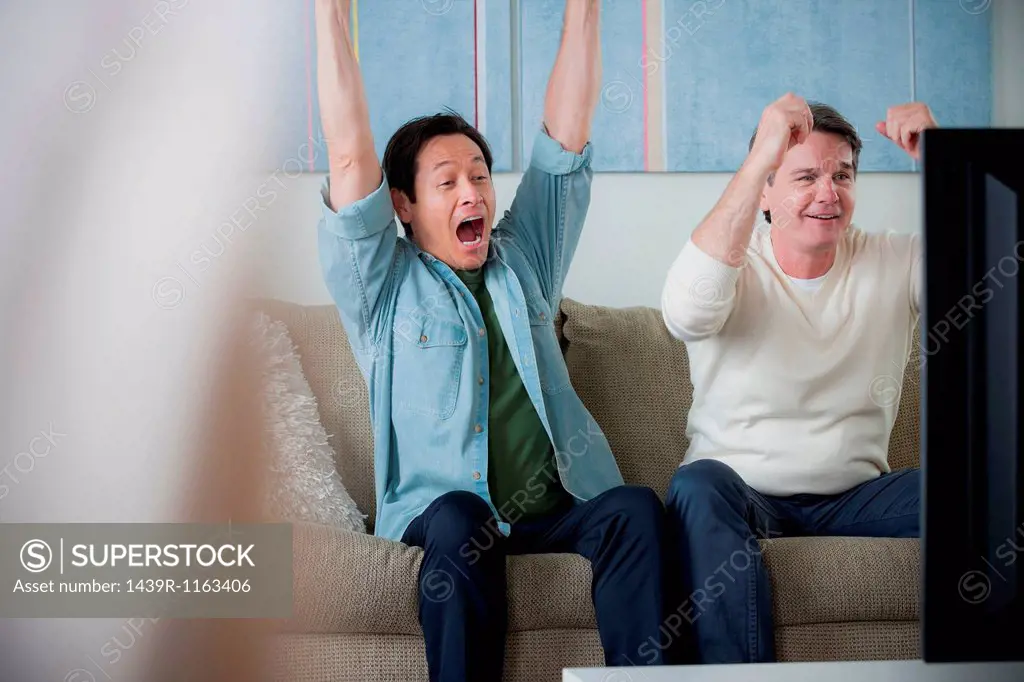 Mature men watching tv, cheering