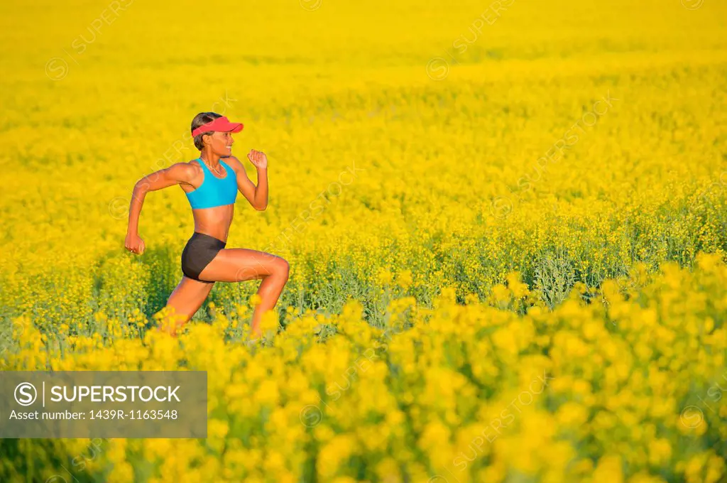 Young woman running in oil seed rape field
