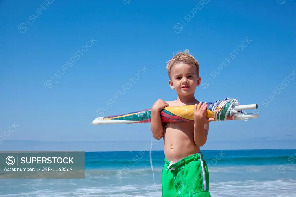 Male toddler holding sun umbrella