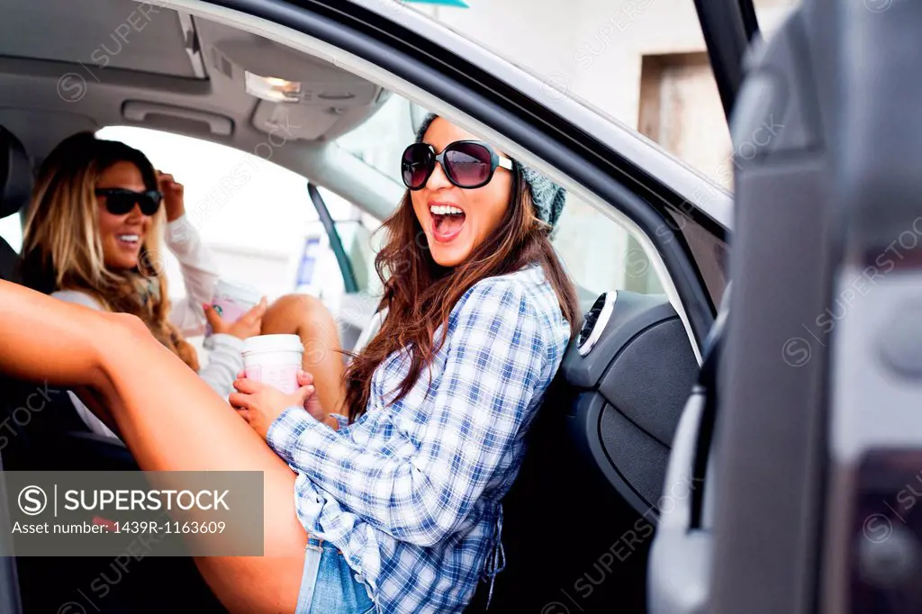 Two female friends in car with takeaway drinks