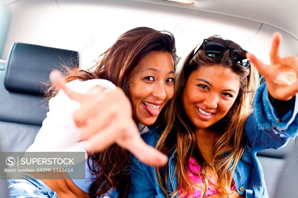 Two female friends making hand gestures in car
