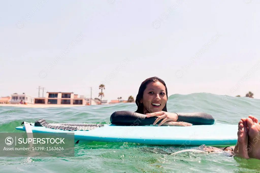 Woman floating with surfboard, Hermosa Beach, California, USA