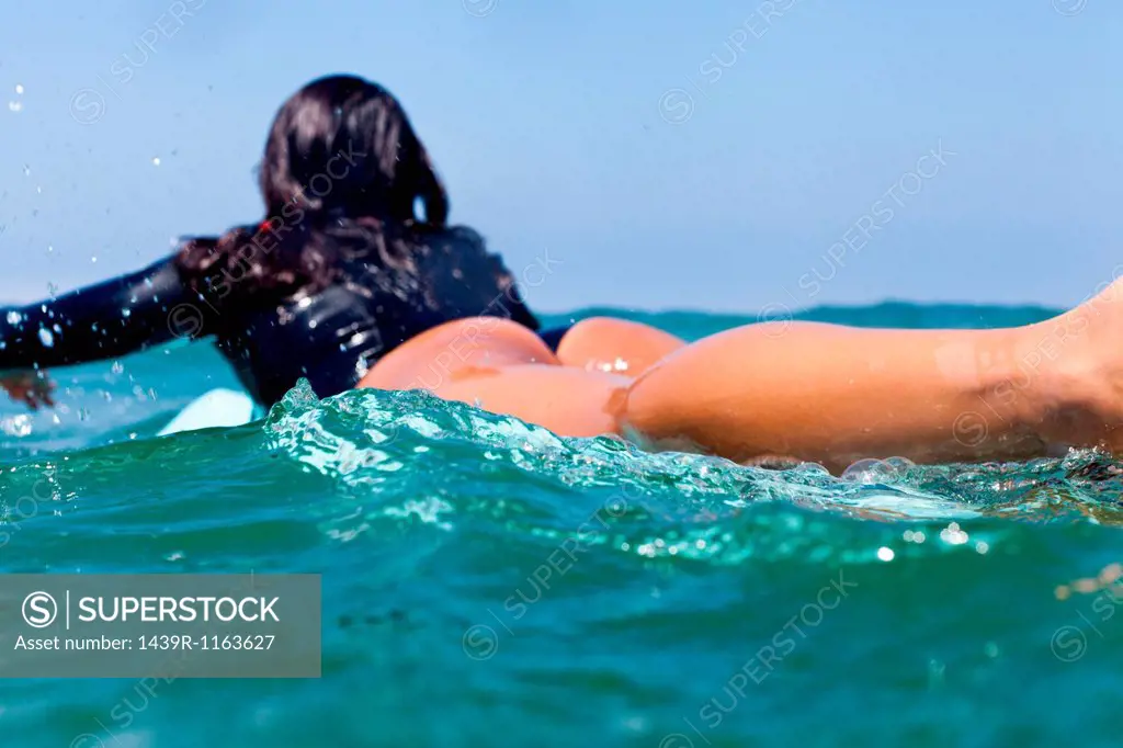 Young woman lying on surfboard, Hermosa Beach, California, USA
