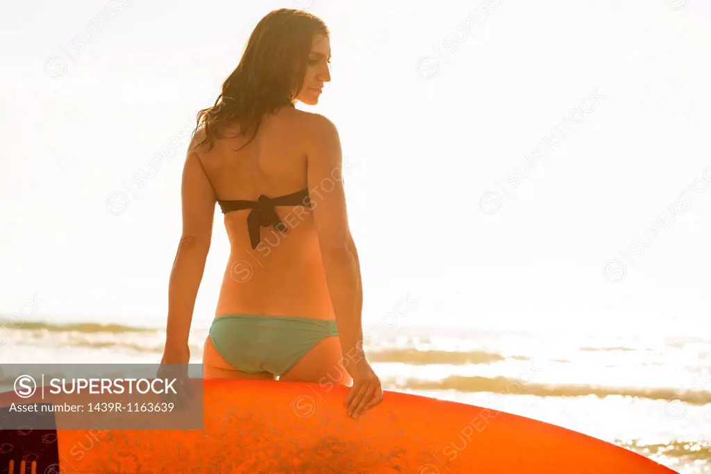 Young woman holding surfboard, La Jolla, San Diego, California, USA