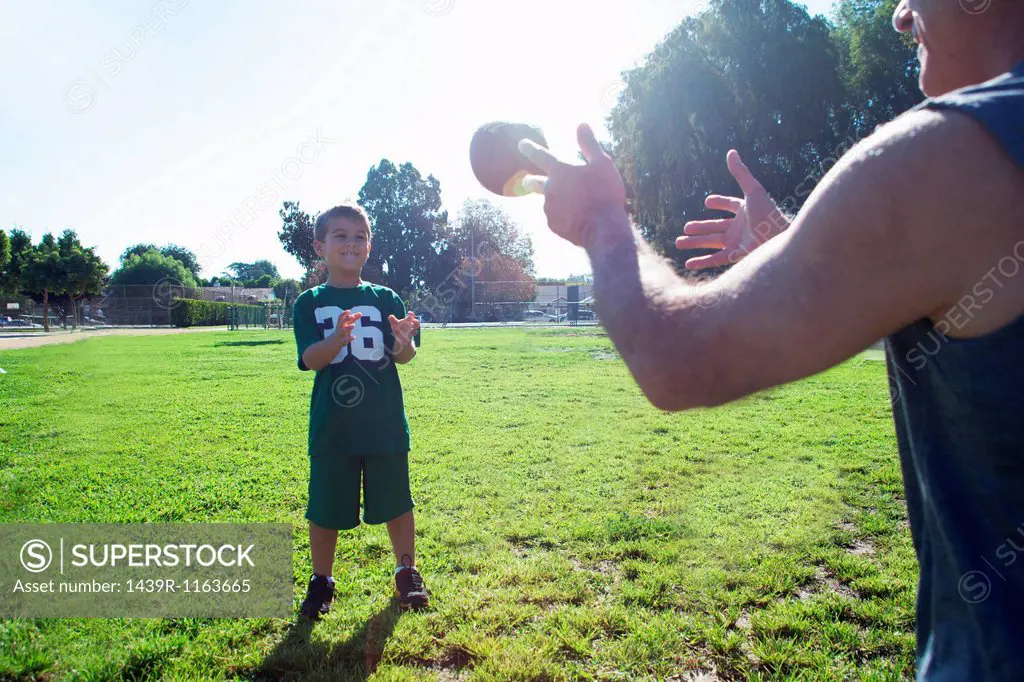 Boy and grandfather playing catch with football
