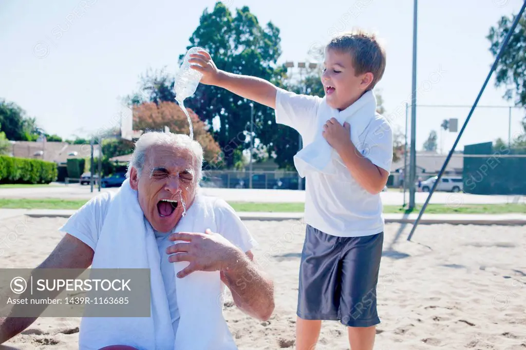 Boy pouring water on grandfather