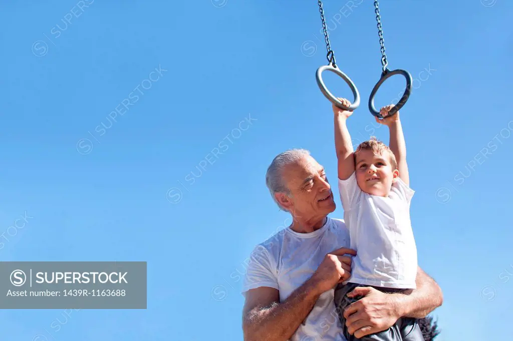 Grandfather holding grandson on gymnastic rings