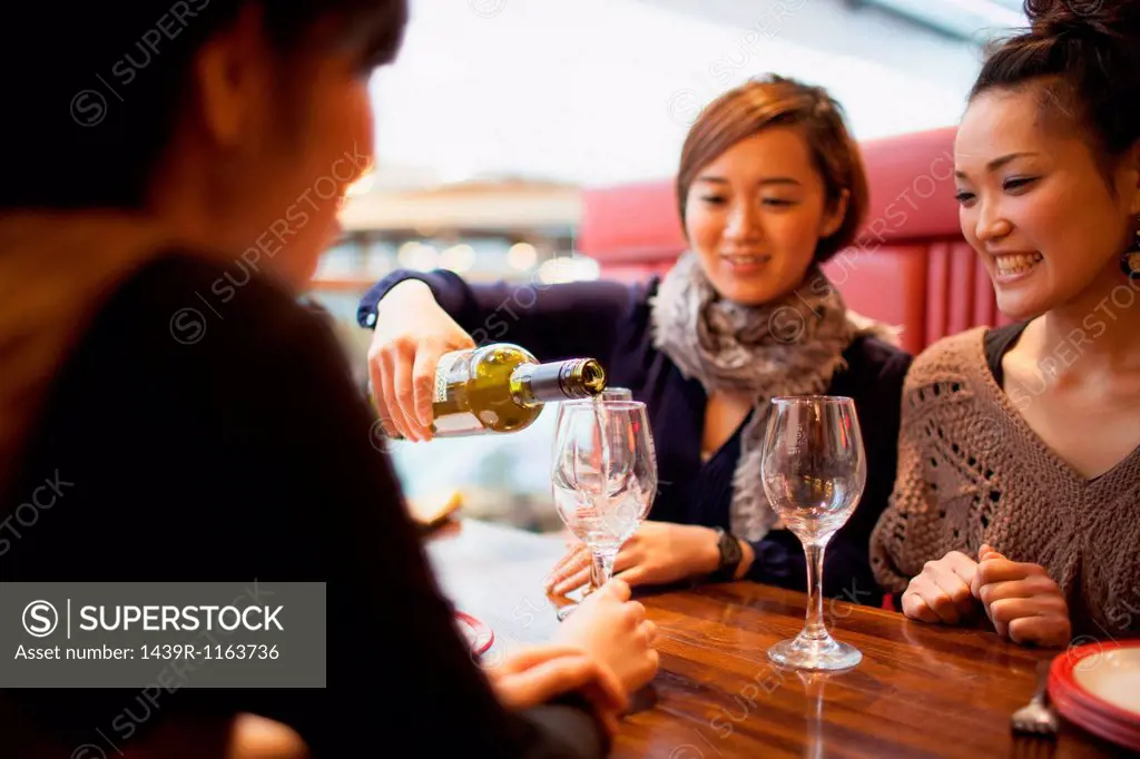 Young woman pouring wine in restaurant