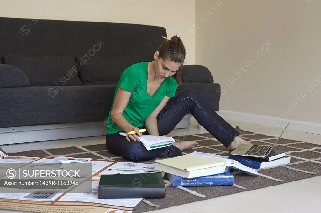 Mid adult woman sitting on floor studying