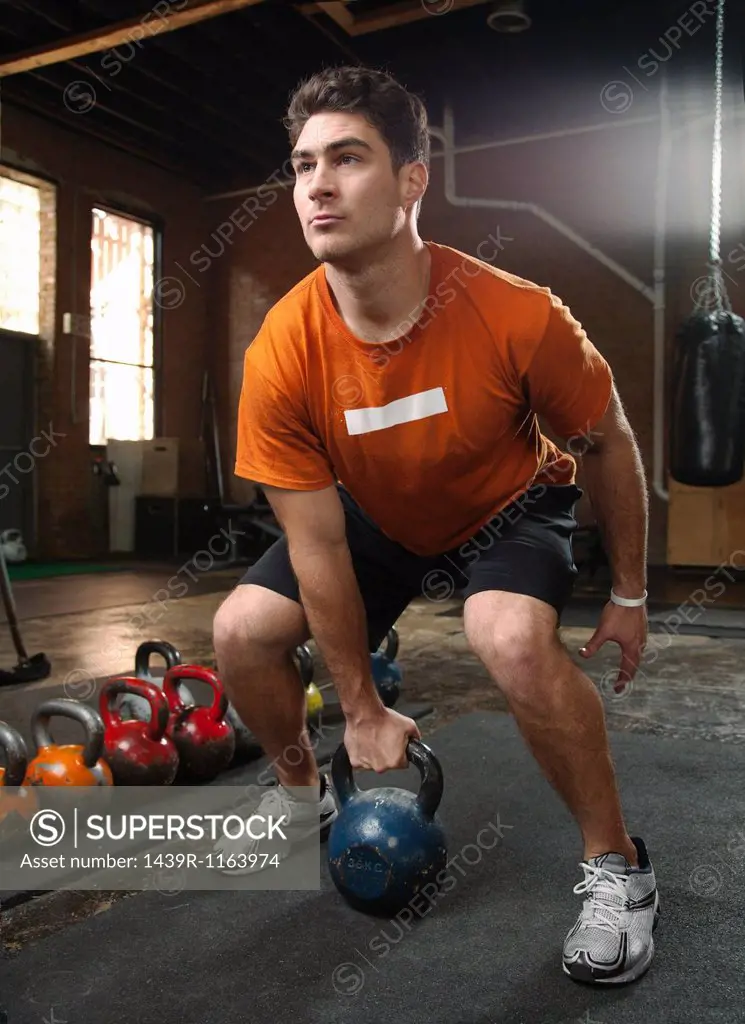 Bodybuilder lifting kettlebells in gym