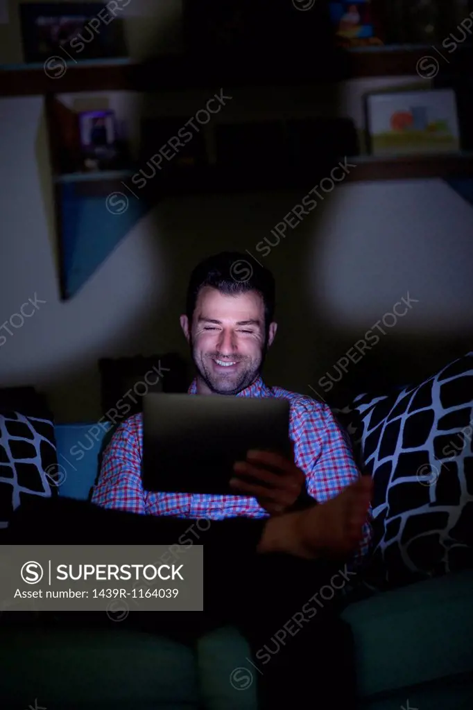 Man sitting on sofa using digital tablet