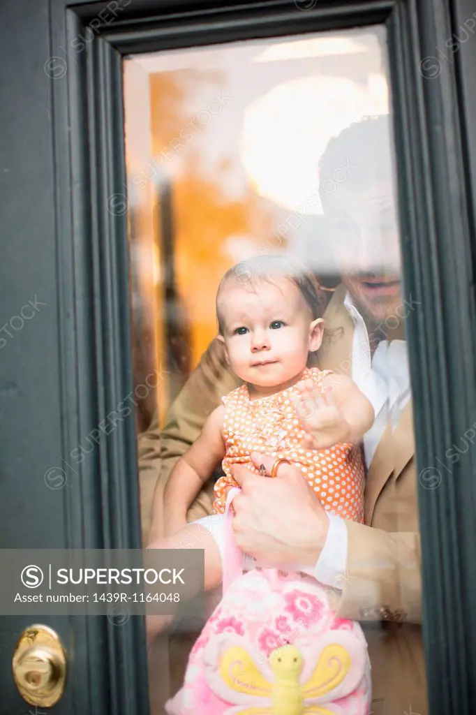 Man holding baby looking through front door