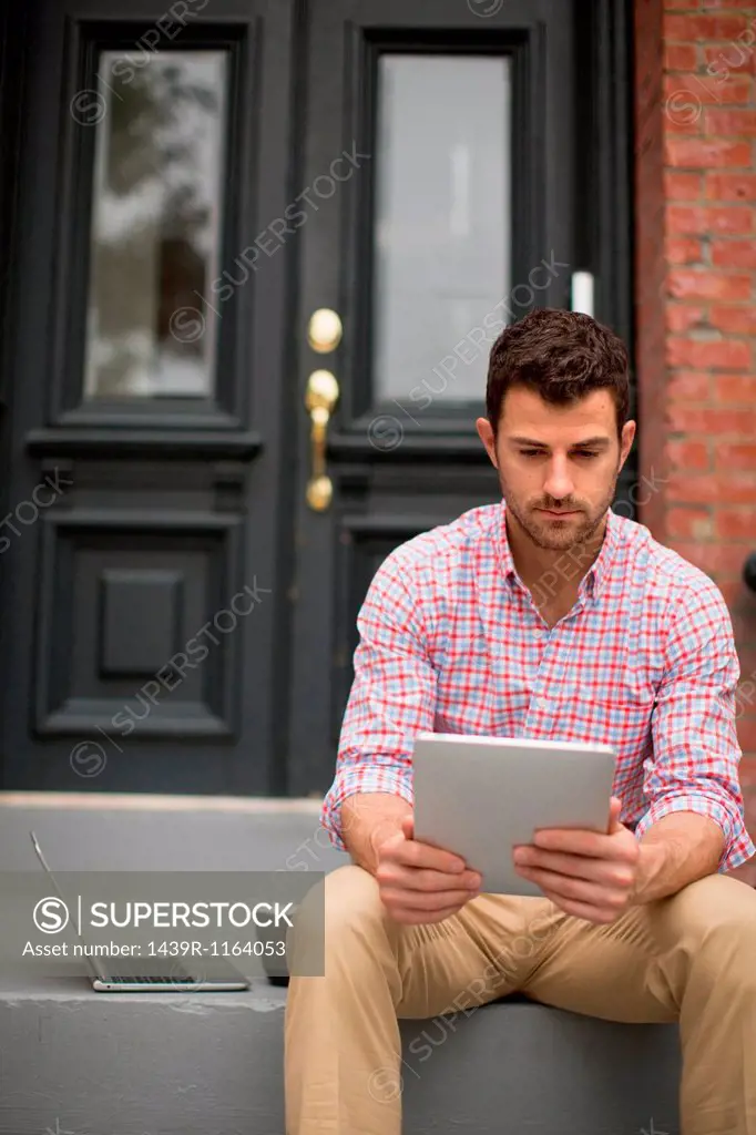 Man sitting on step using digital tablet