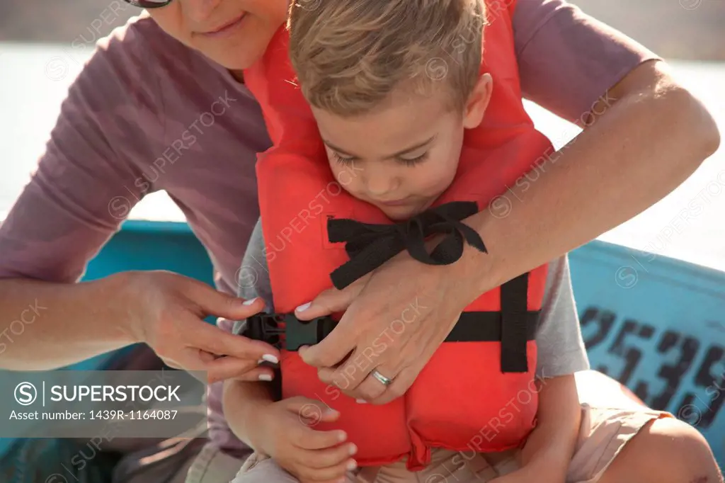 Mother fastening son´s life jacket