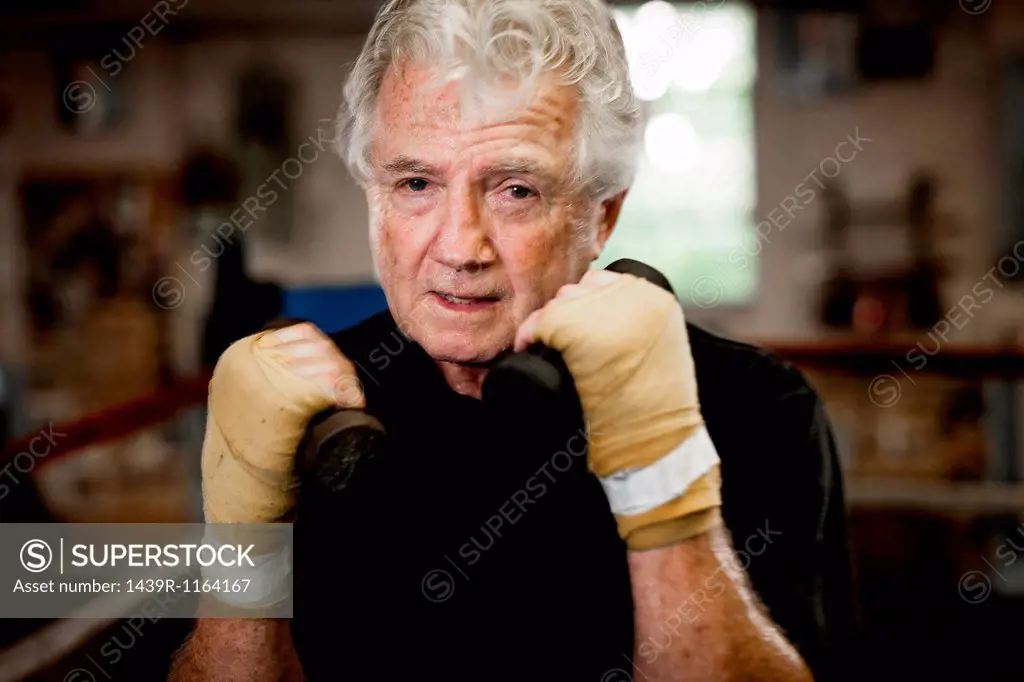 Senior man wearing gloves, lifting weights