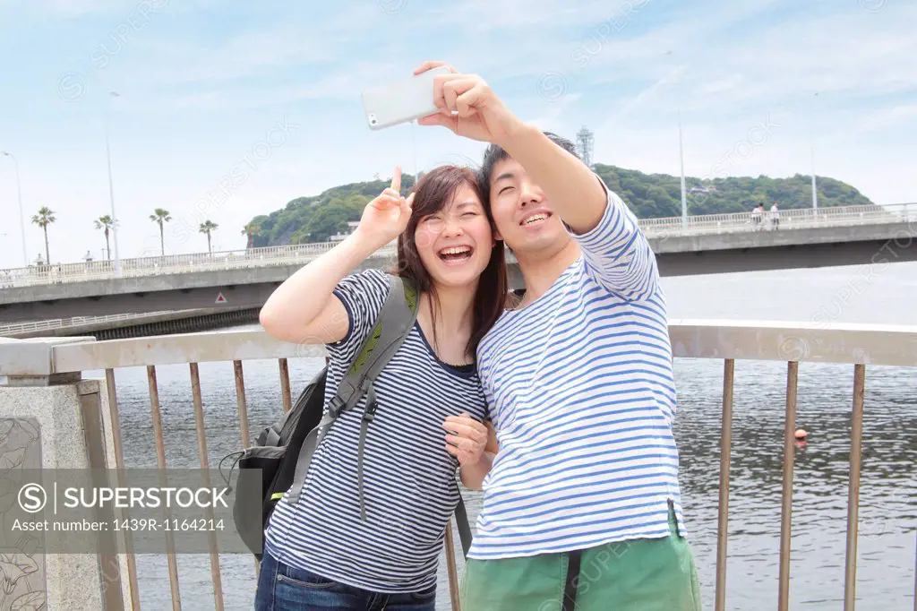 Young couple taking self portrait photograph with smartphone