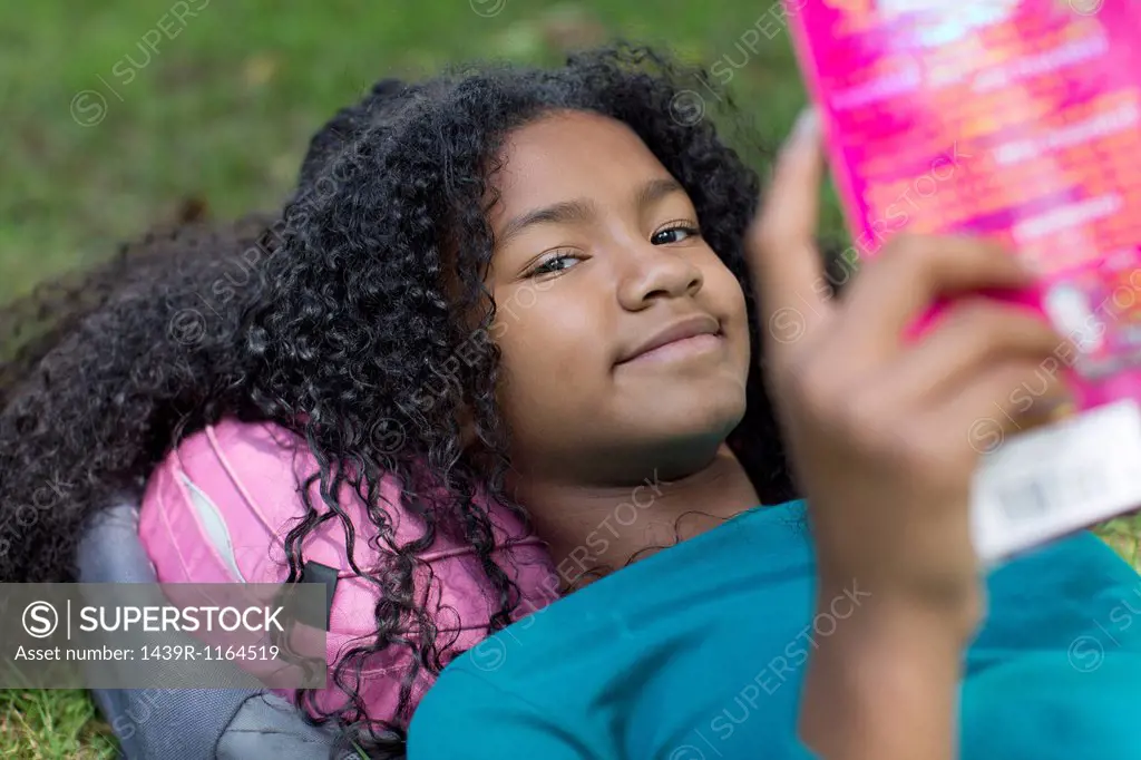 Close up portrait of young girl reading in park