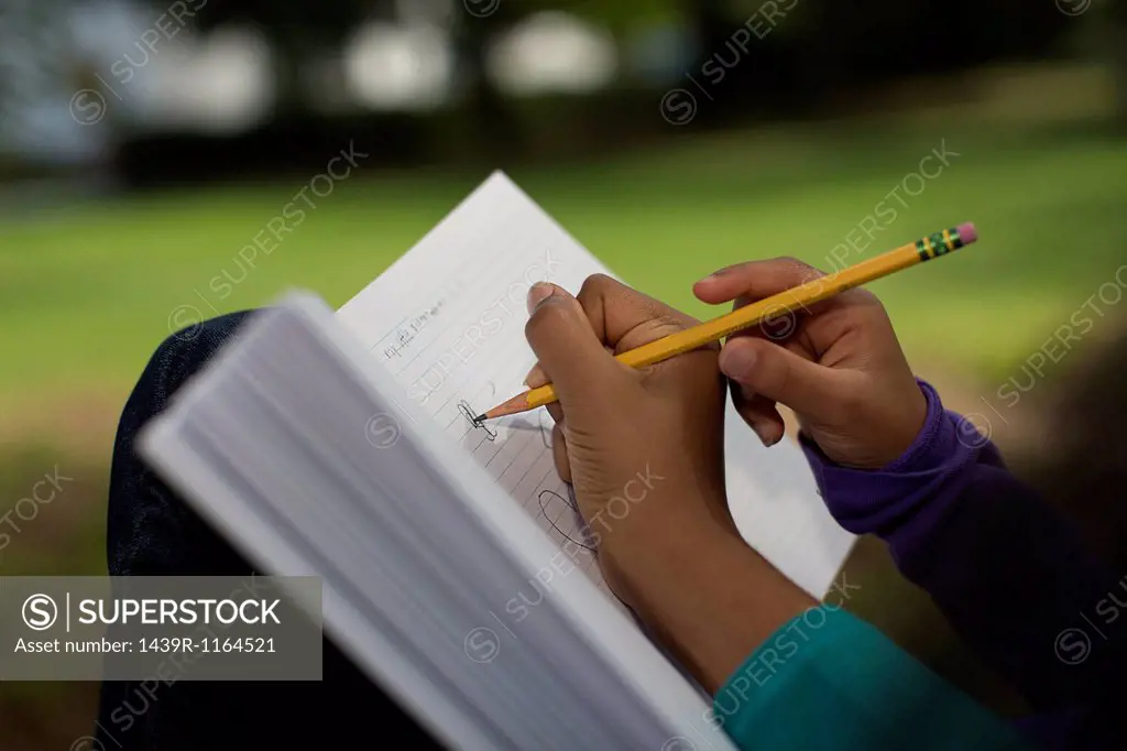 Close up of sisters in park writing in notebook