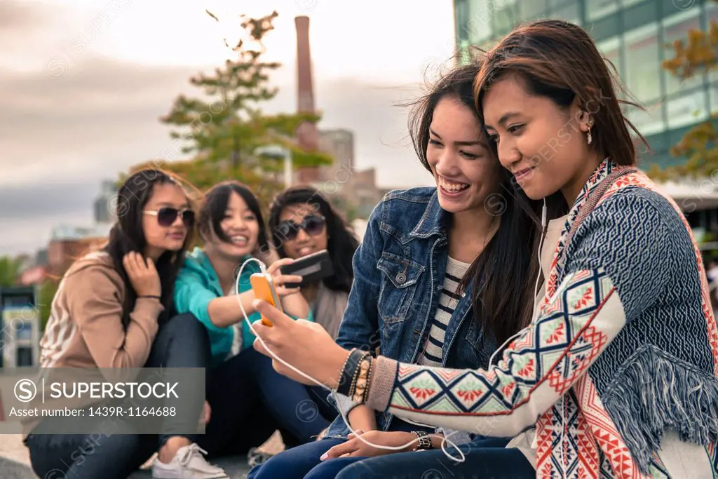 Young women taking self portrait photographs using smartphones