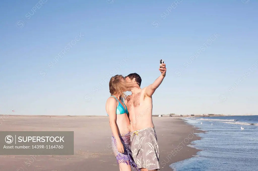 Couple taking self portrait on beach, Breezy Point, Queens, New York, USA