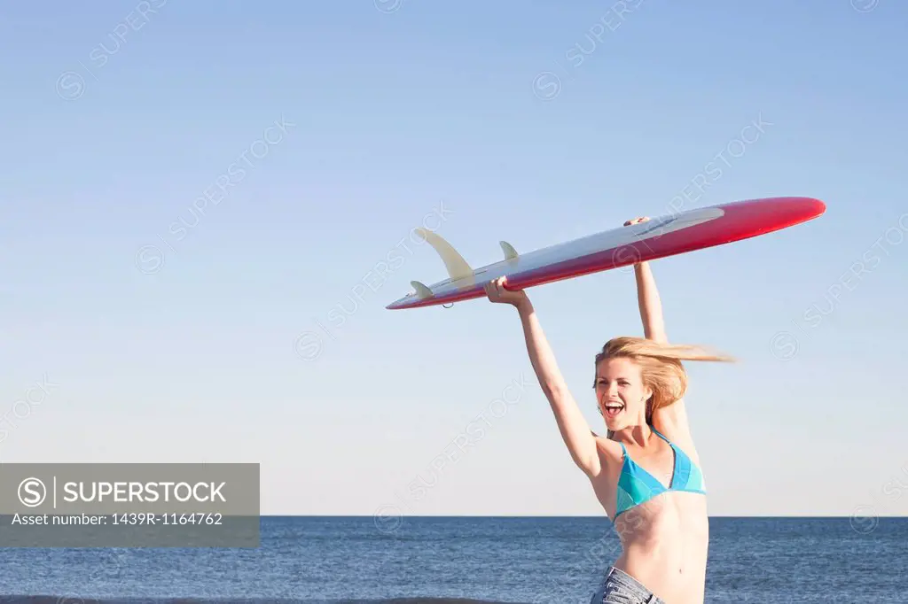Young woman holding surfboard up, Breezy Point, Queens, New York, USA