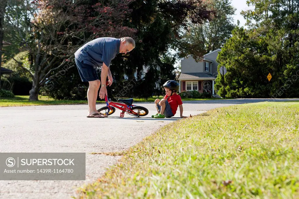 Grandfather picking up young boys bicycle