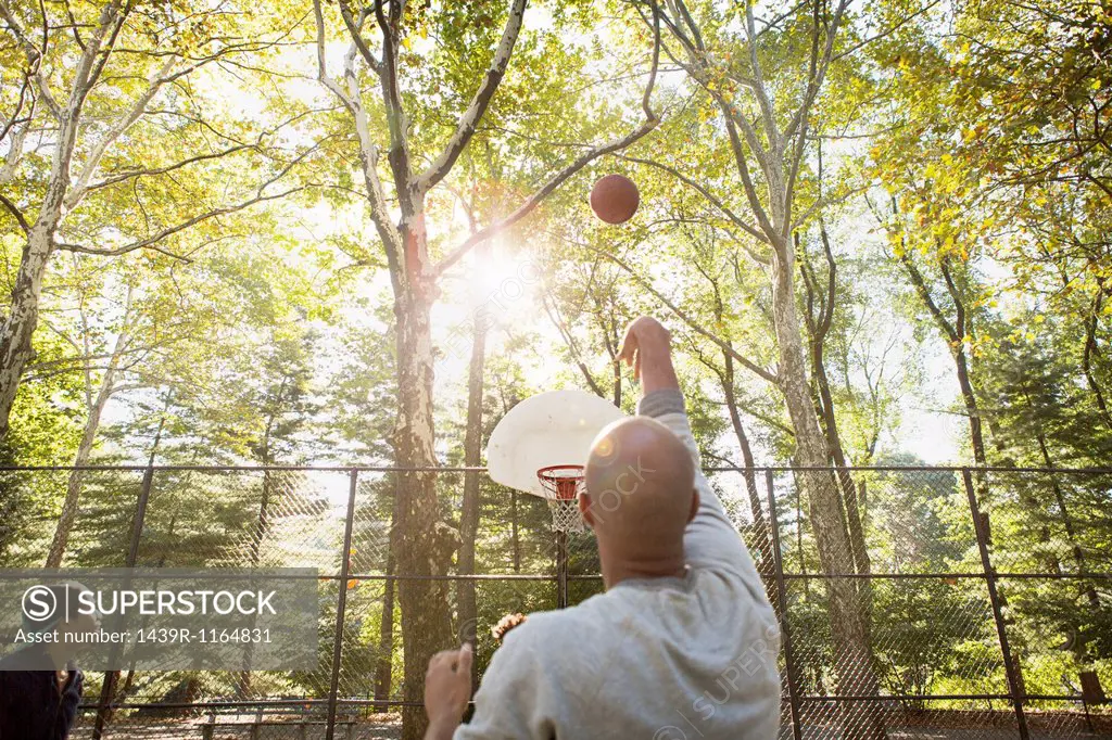 Young man throwing basketball towards goal