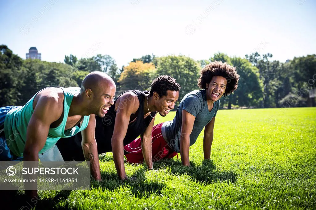 Three young men doing push ups in park