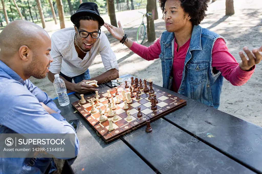 Three young men playing chess in park