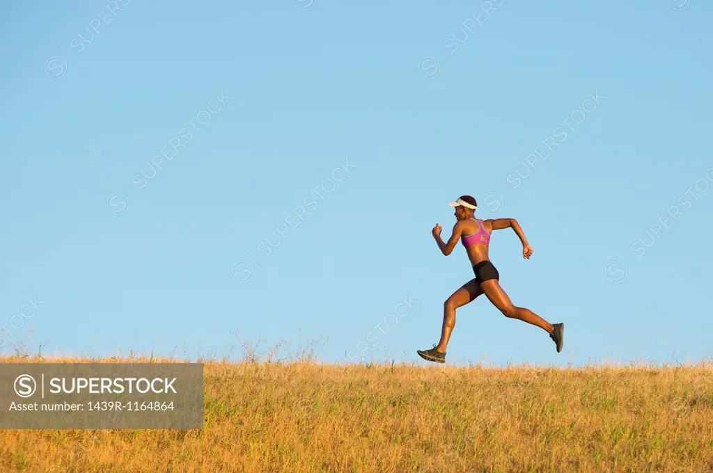 Young woman running across field