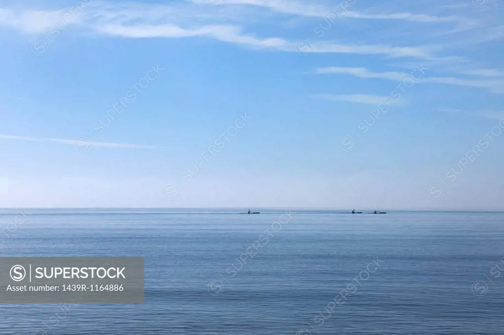 Three sea kayakers on horizon, Poole, Dorset, UK