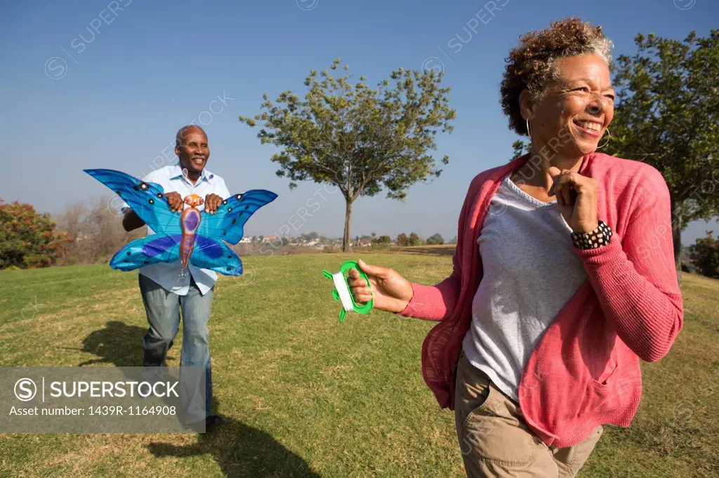 Senior couple running in park with kite