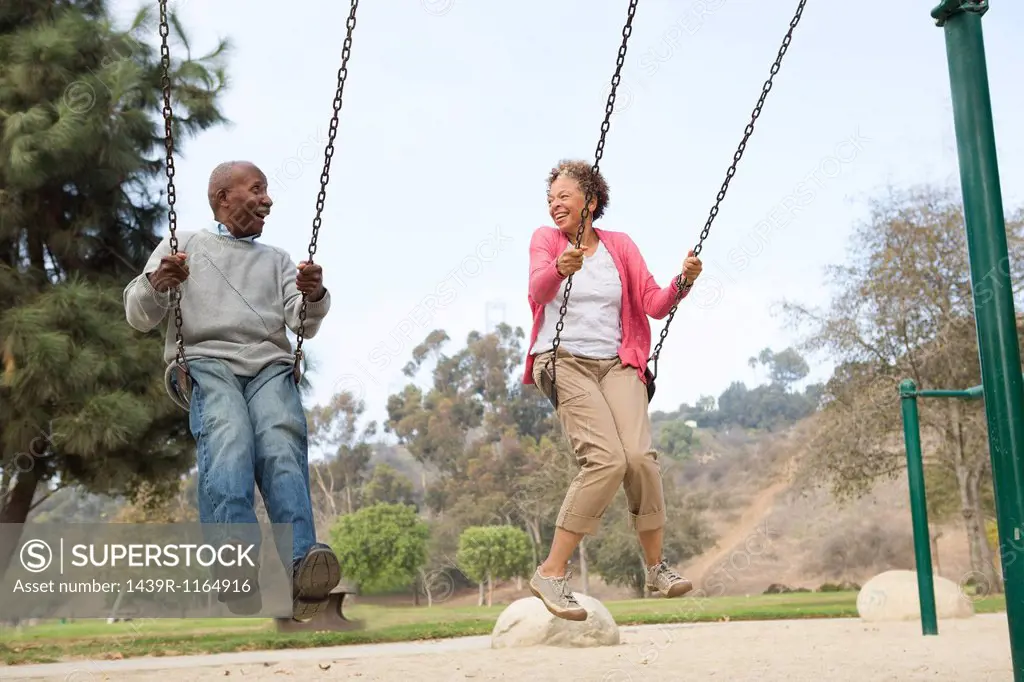 Senior couple on swings in park