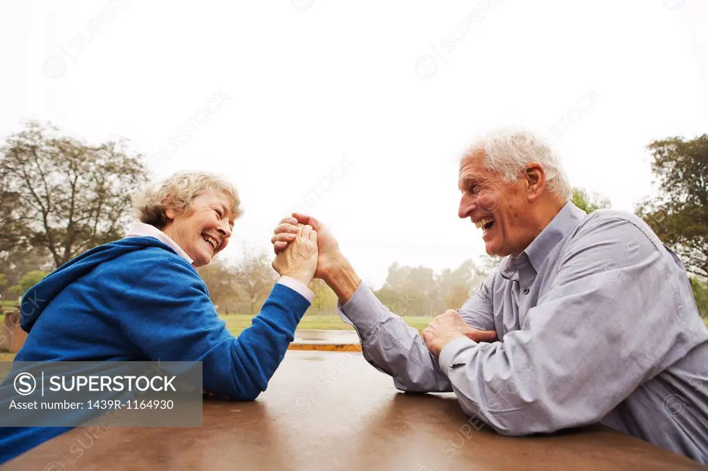 Husband and wife arm wrestling in the park