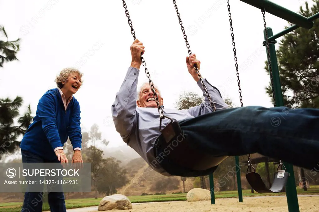 Wife pushing husband on swing