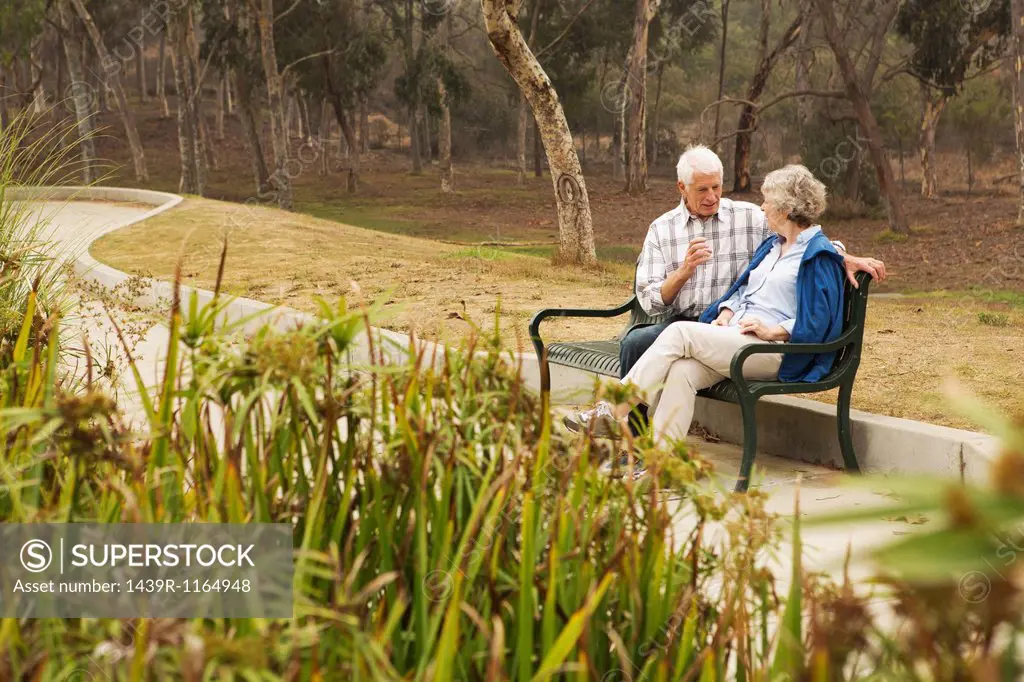 Husband and wife chatting lovingly on park bench