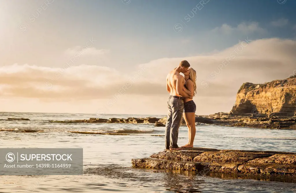 Young couple kissing on rocks, Sunset Cliffs, San Diego, California, USA