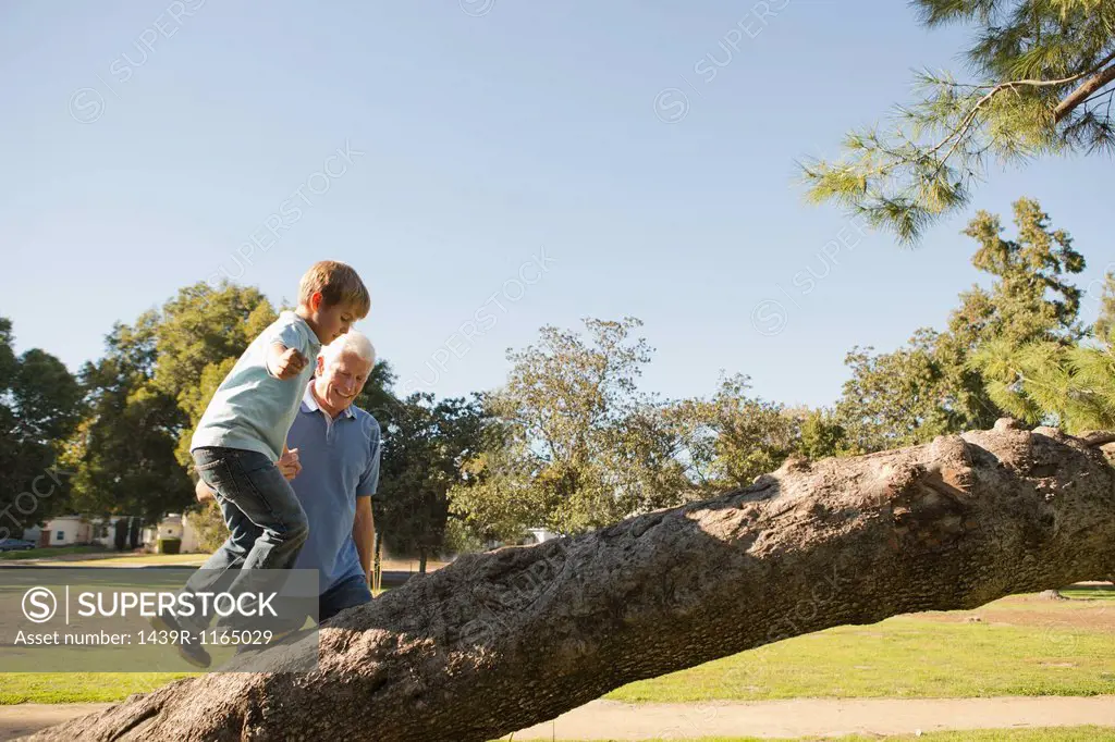 Grandfather helping grandson to climb tree