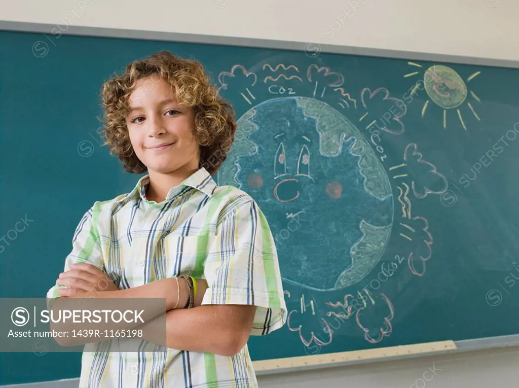 Boy standing by blackboard