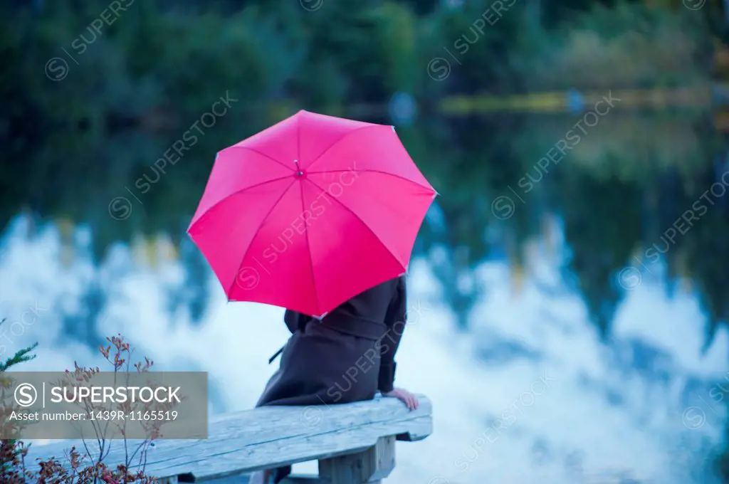 Woman with pink umbrella by lake, Bellingham, Washington, USA