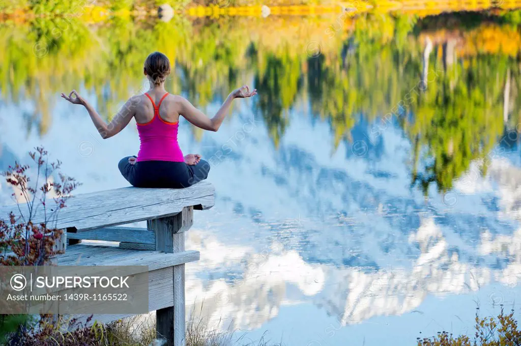 Woman meditating by lake, Bellingham, Washington, USA