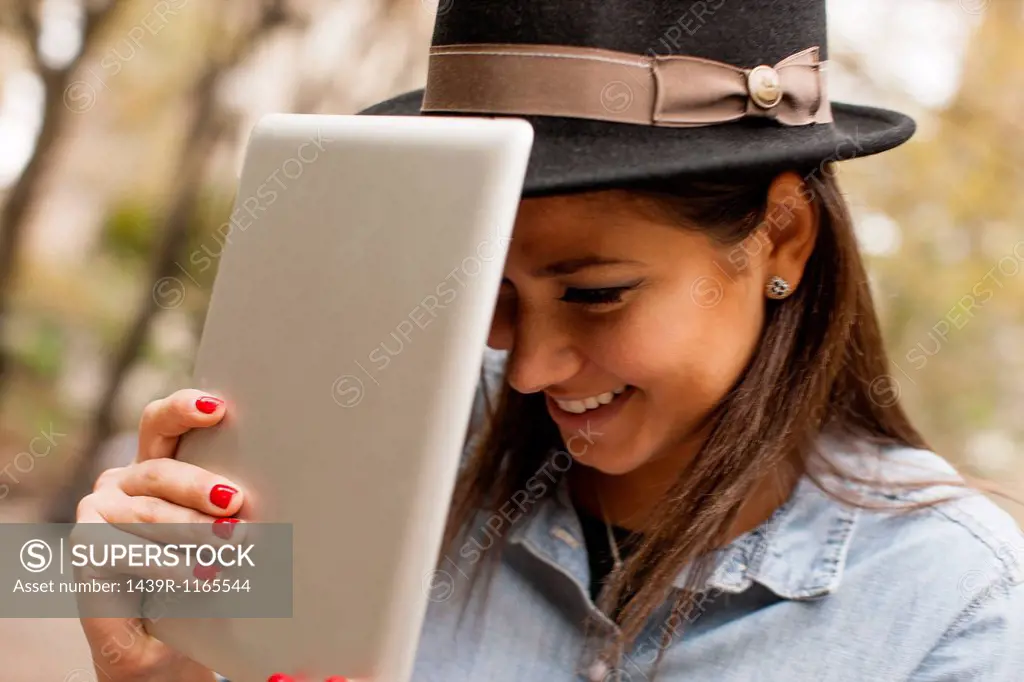 Woman holding digital tablet to hat