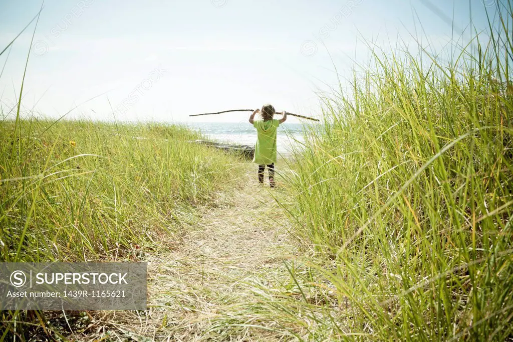 Female toddler carrying long stick