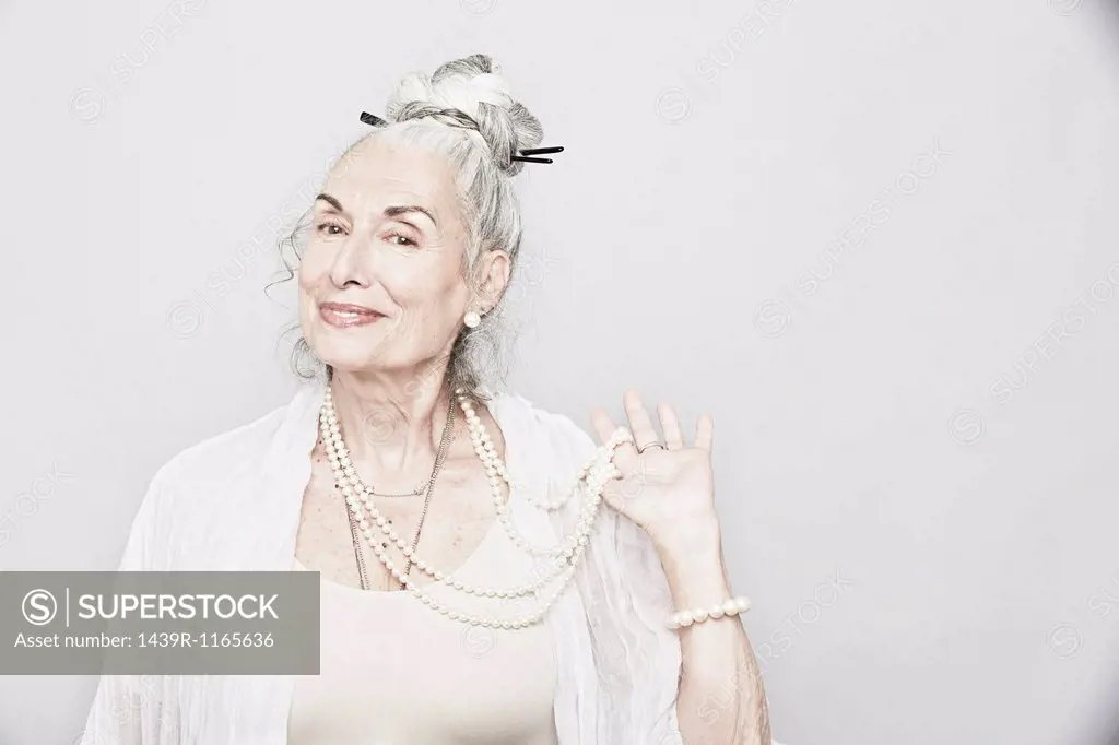 Studio portrait of sophisticated senior woman holding beads