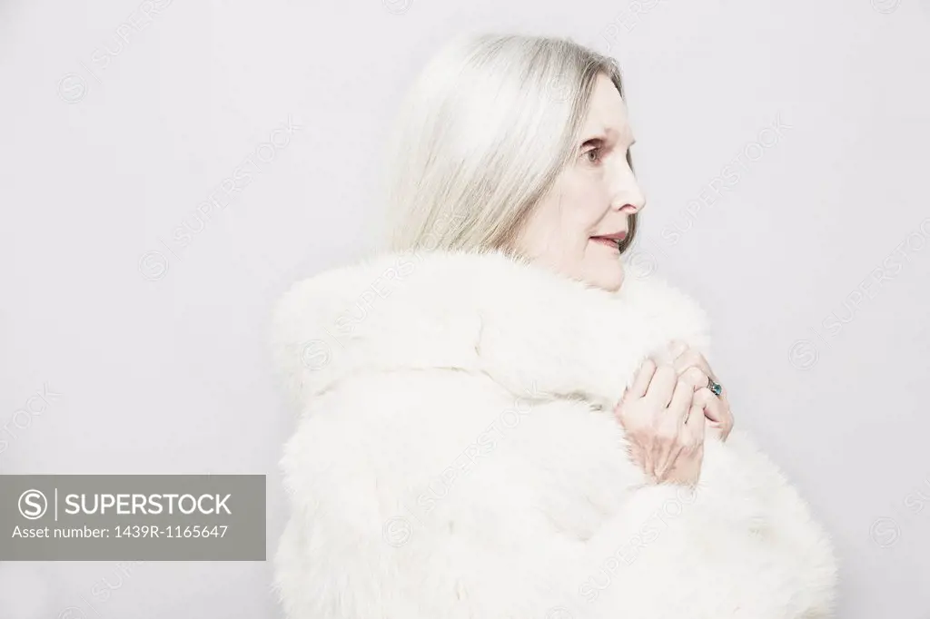 Studio portrait of senior woman in white fur coat