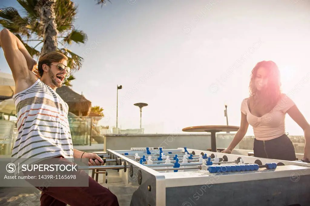 Young couple playing table football at San Diego beach