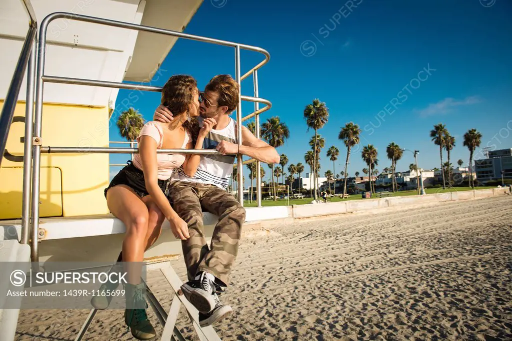 Young couple sitting kissing at San Diego beach