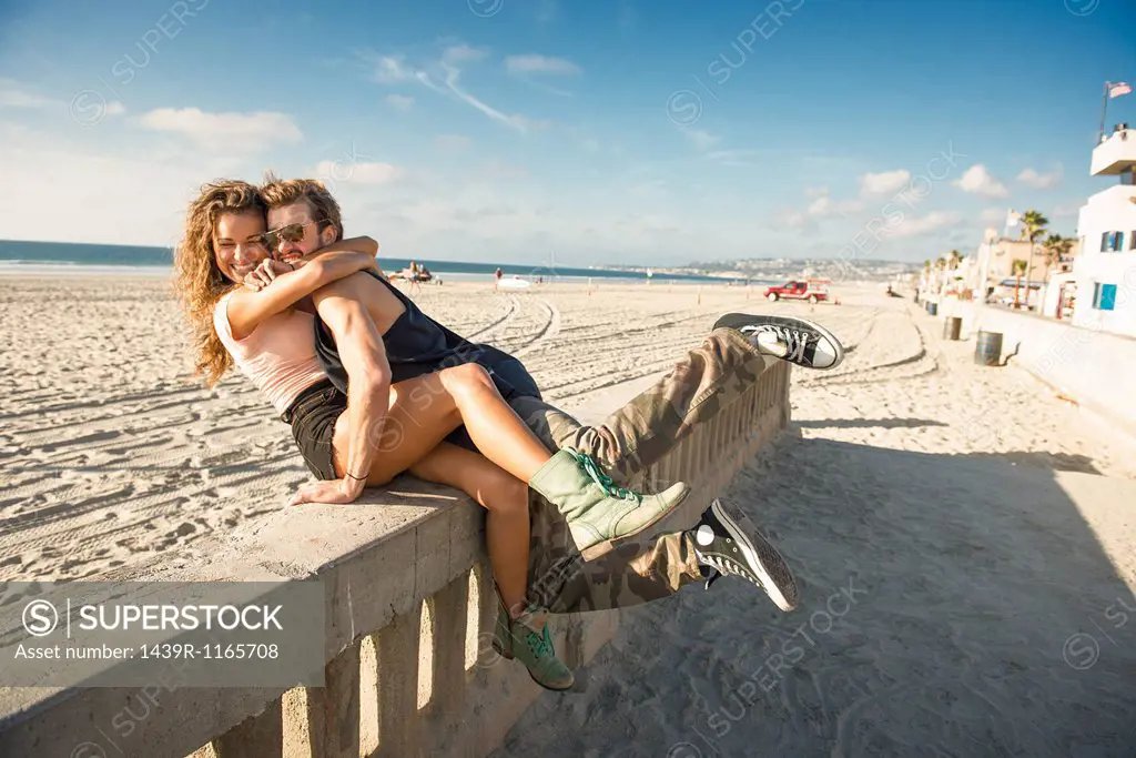 Young couple hugging on wall at San Diego beach